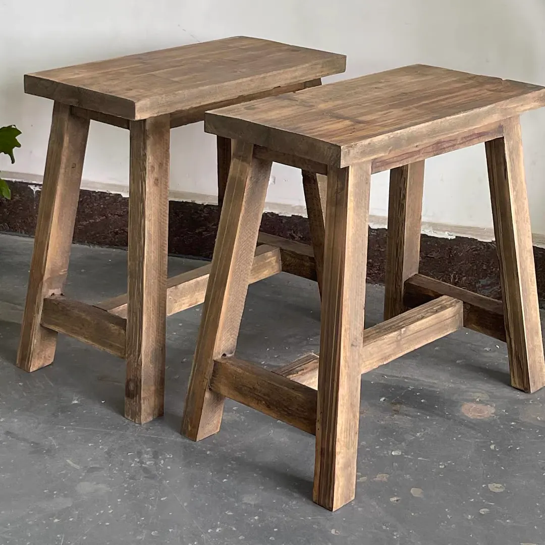 Two rustic fir wood stools side by side against a white wall